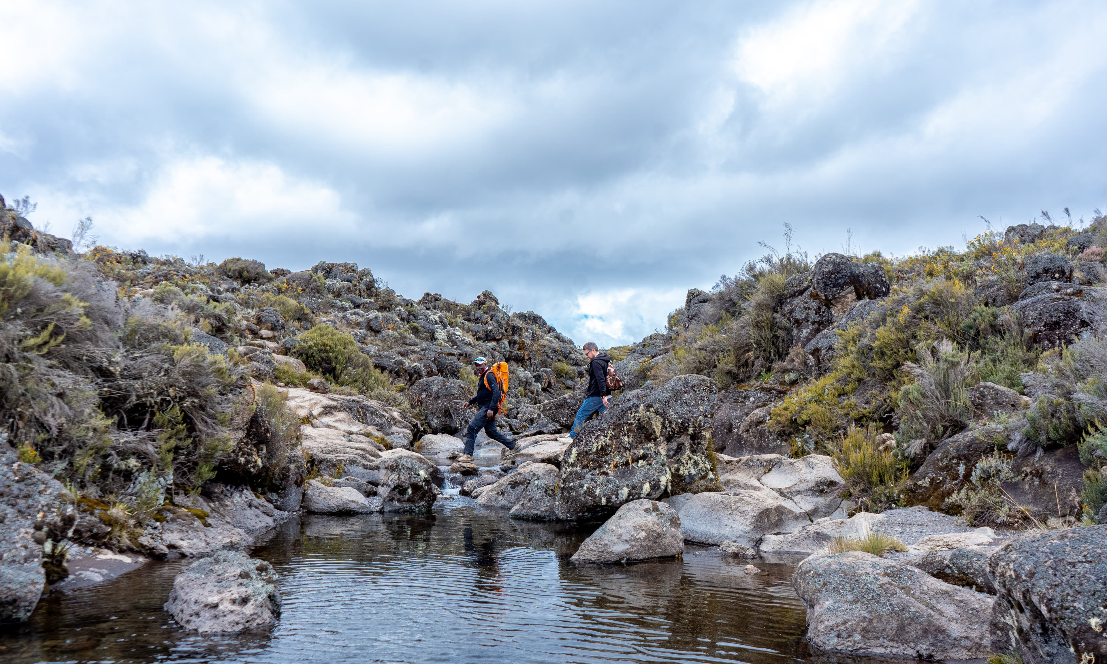 Climbers following a high-altitude mountain stream